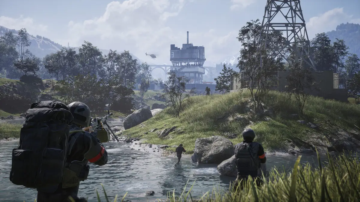 Four soldiers wading across a stream toward an industrial building in a mountain valley